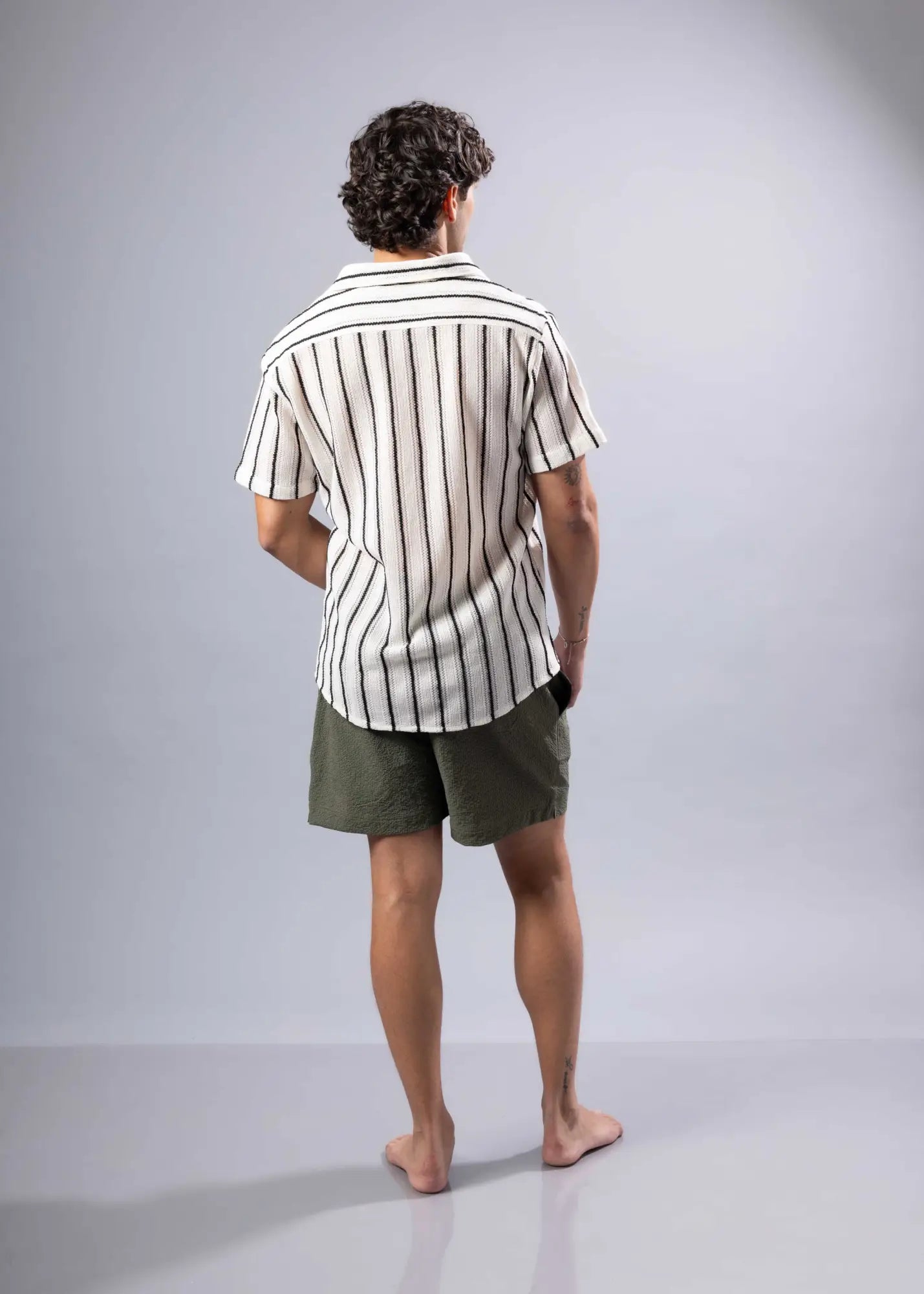 A man wearing a short-sleeved texture knit shirt with vertical black and white stripes