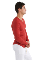 A man wearing a vibrant cinnabar thermal v-neck long sleeve shirt made of smooth fabric