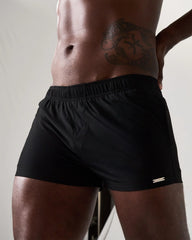 Black statement swim short with elastic waistband and small metallic logo on the lower right leg