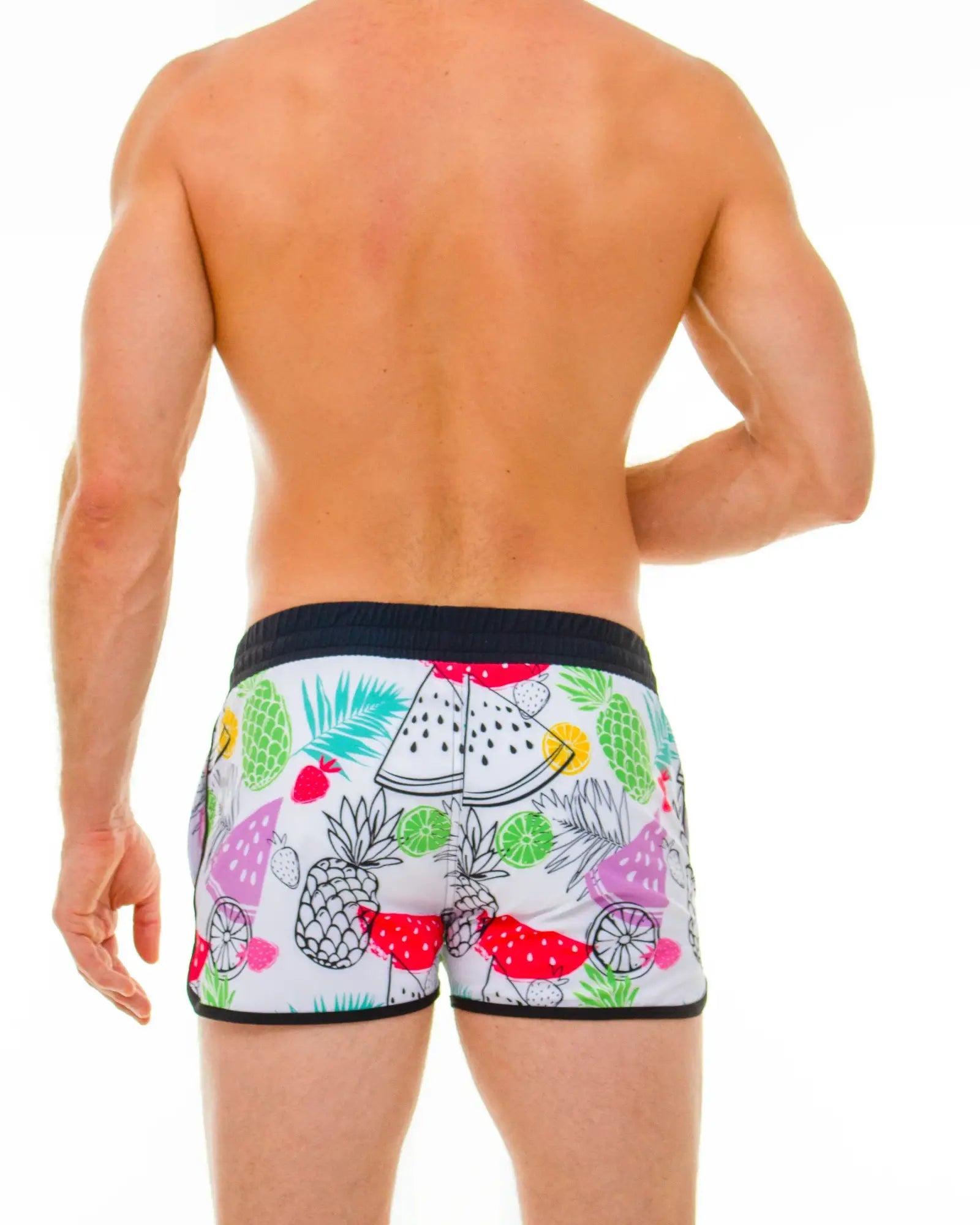 White swim trunks with a vibrant tropical fruit pattern of pineapples watermelons and limes in bright colors