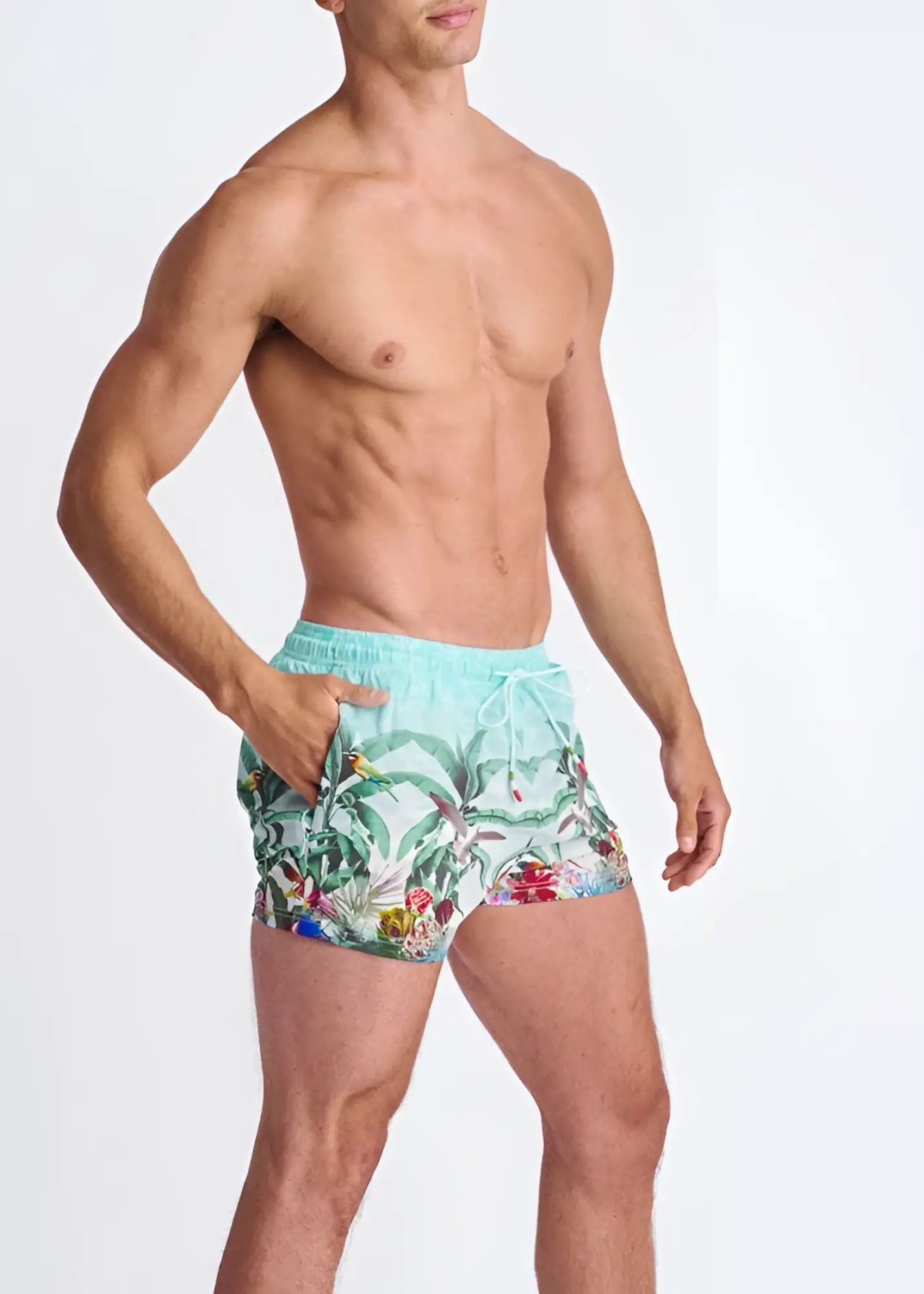 Light blue tropics print swim shorts with mesh lining featuring green leaves red flowers and colorful birds tropical design