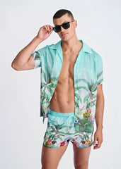 A vibrant turquoise tropical print swim shorts with mesh lining featuring palm leaves and birds pattern
