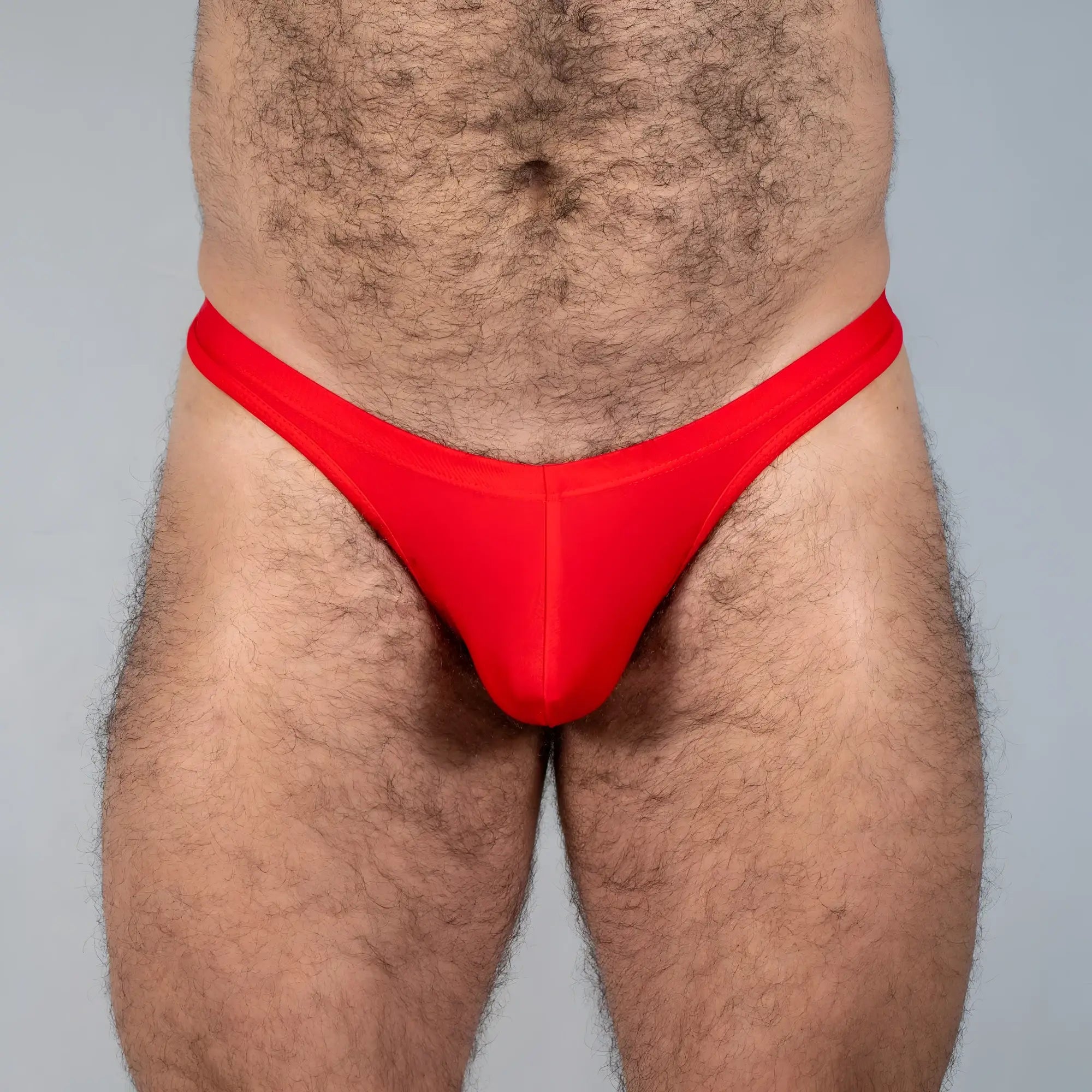 Bright red tulio swim thong made of smooth stretchy fabric in a form-fitting solid design shown from the back side