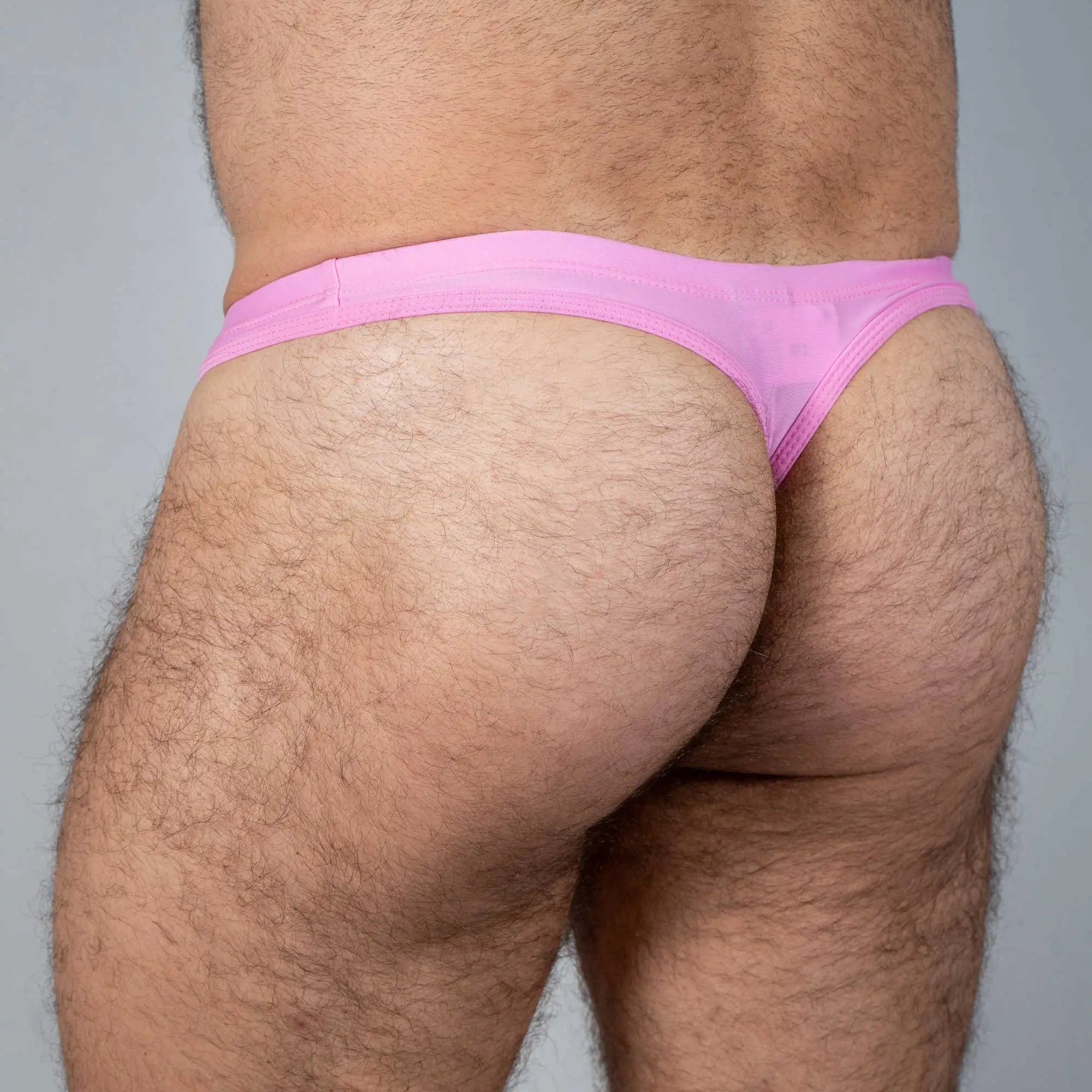 Pink tulio swim thong made of sheer fabric showcasing the front solid design for swimwear use