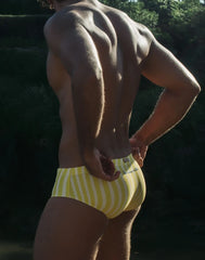 Yellow and white striped men’s swim trunks with a small logo on the waistband for beachwear and swimming