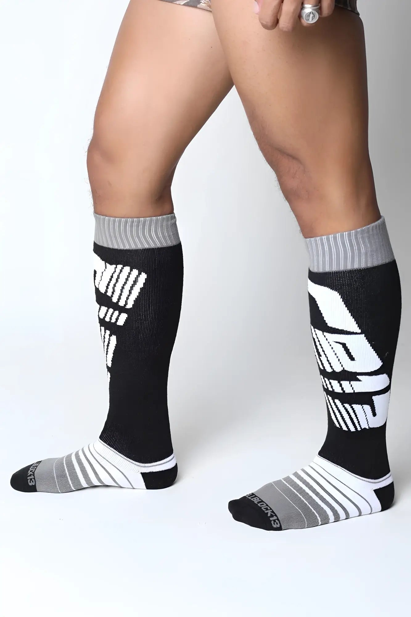 Black and gray athletic knee high socks with bold white graphic lettering on the side from velocity 2.0 collection