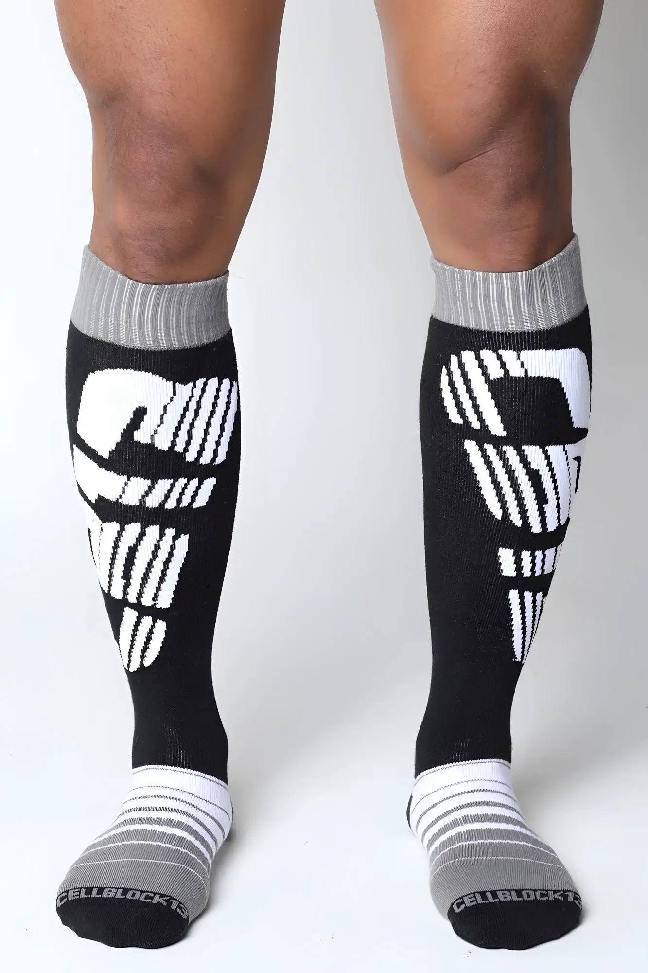 Black and white velocity 2.0 knee high athletic compression socks with stylized skull design on the calf visible from the back