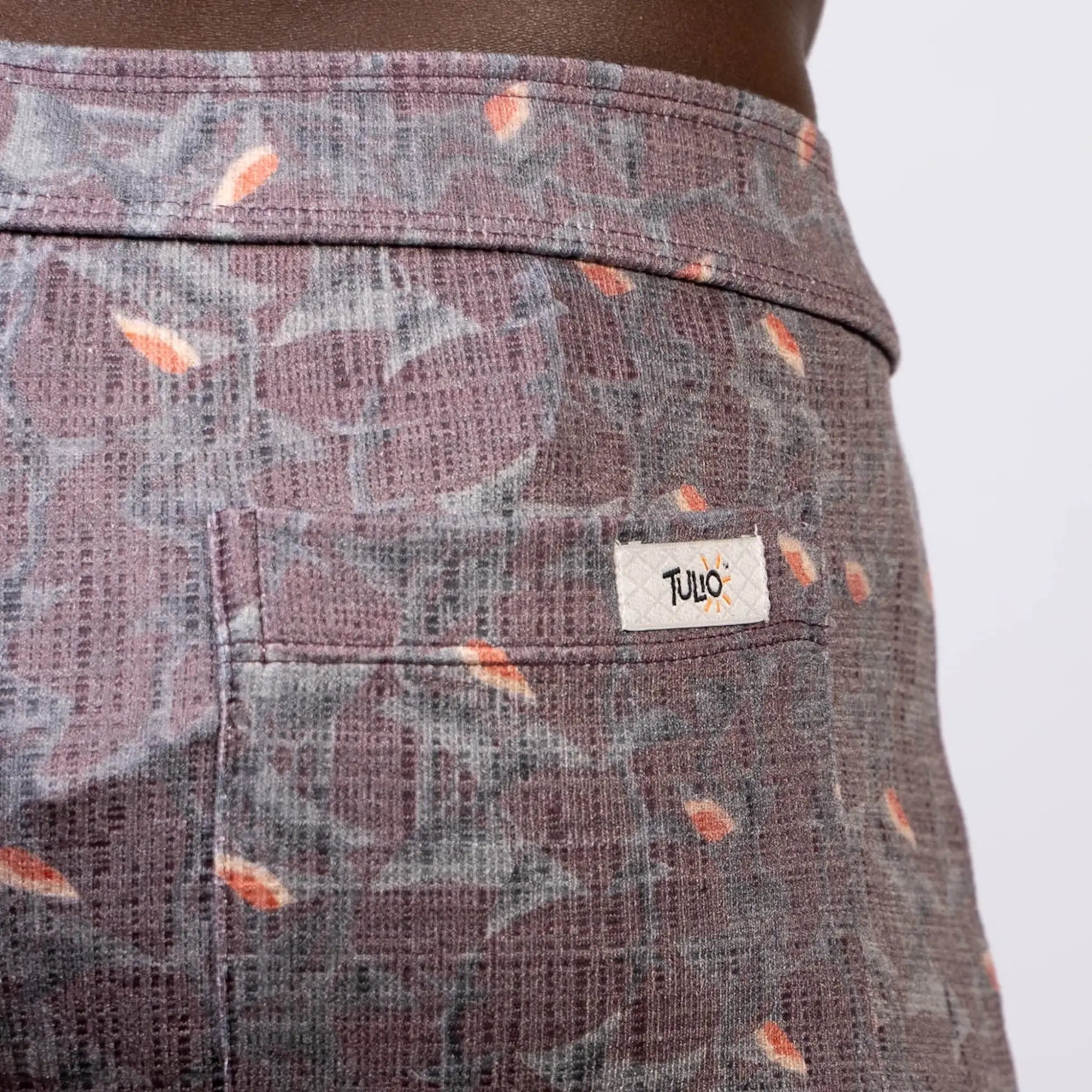 Back view of vintage stripes linen texture shorts in purple and gray with orange leaf accents and a tulo label