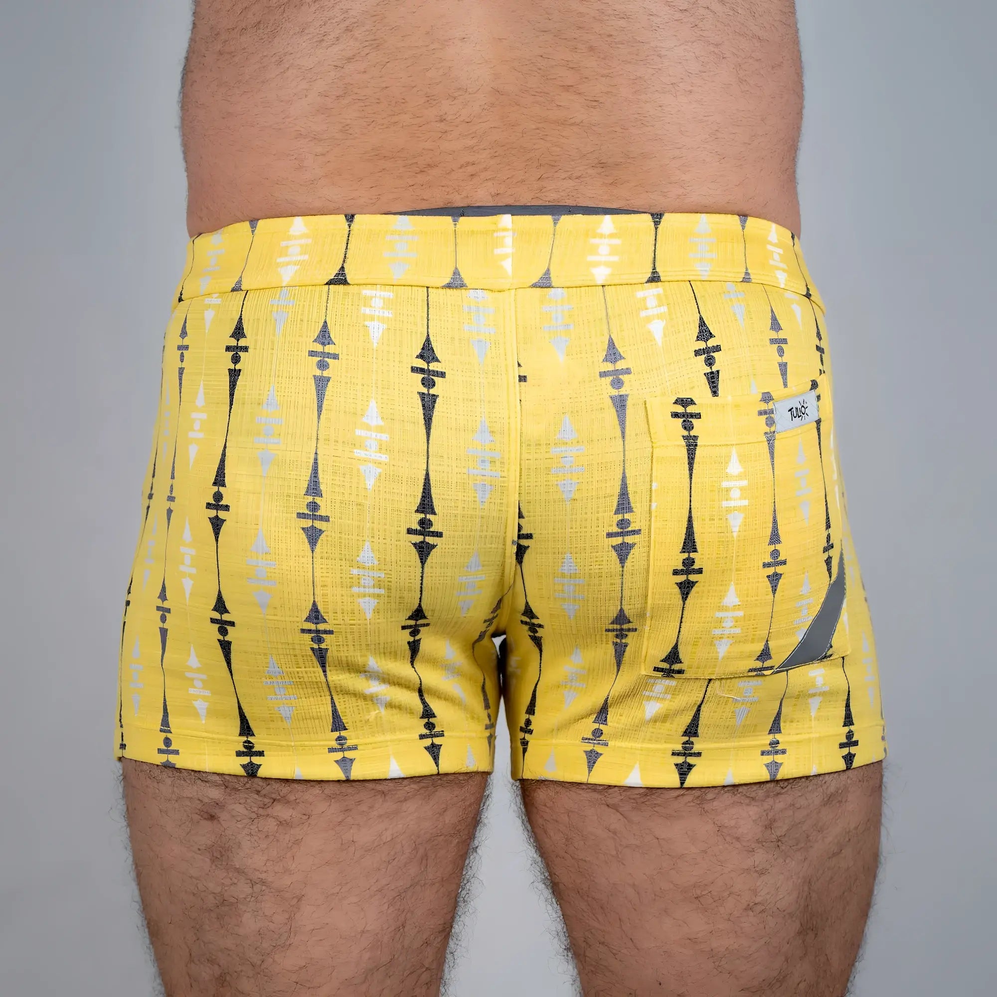 Bright yellow wallpaper print linen texture shorts with bold black and white geometric pattern and branded tag on back pocket
