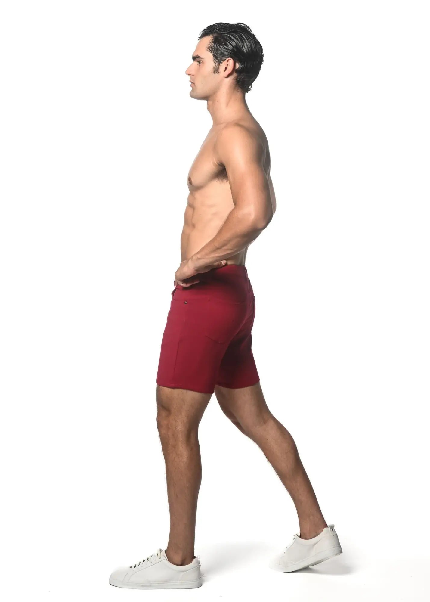 A pair of form-fitting deep red washed denim stretch knit athletic shorts worn by a model