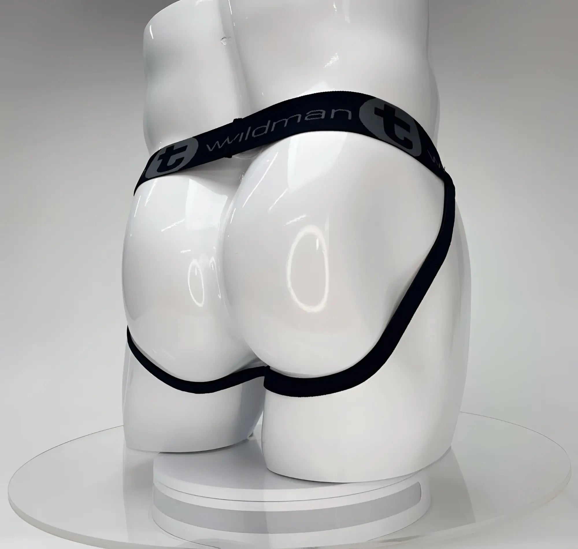 Black elastic waistband with wildman branding on white mannequin wearing wildmant big boy pouch jockstrap white