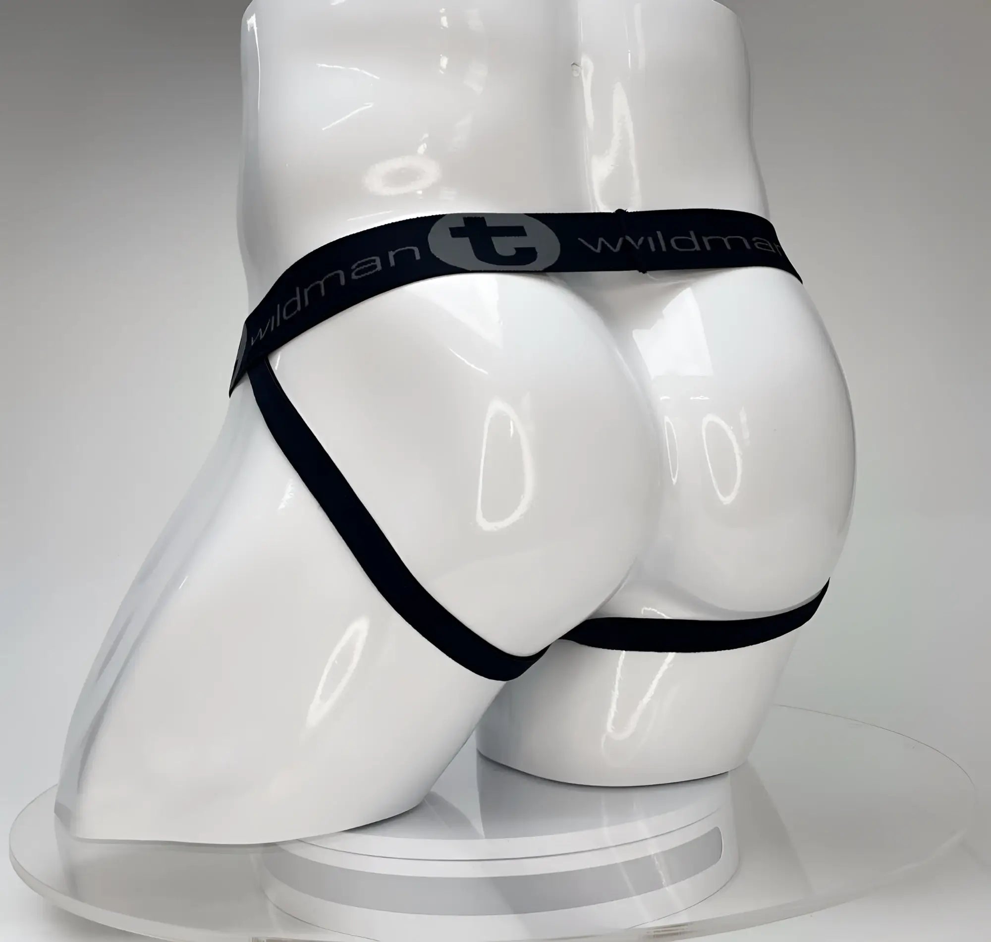 Black elastic waistband with wildman branding on a glossy white mannequin wearing wildmant big boy pouch jockstrap white