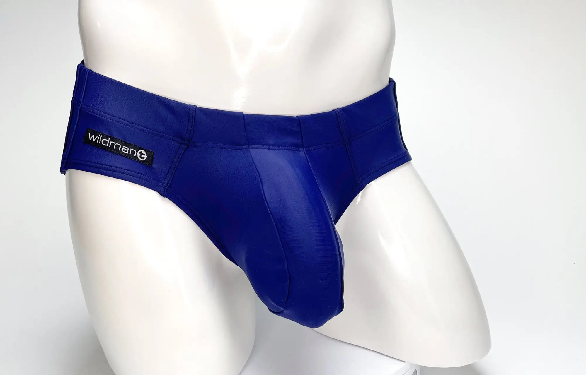 Royal blue glossy latex swim briefs with black wildman brand label on waistband big boy pouch design