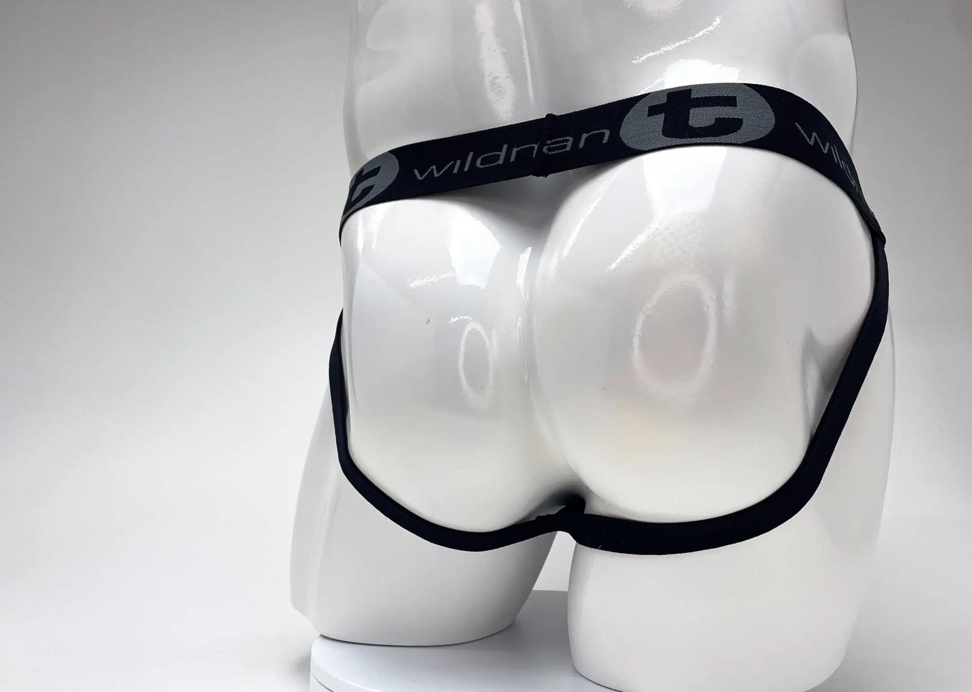 Black elastic waistband with wildnan branding on white mannequin of wildmant cotton big boy pouch stripe jockstrap red black