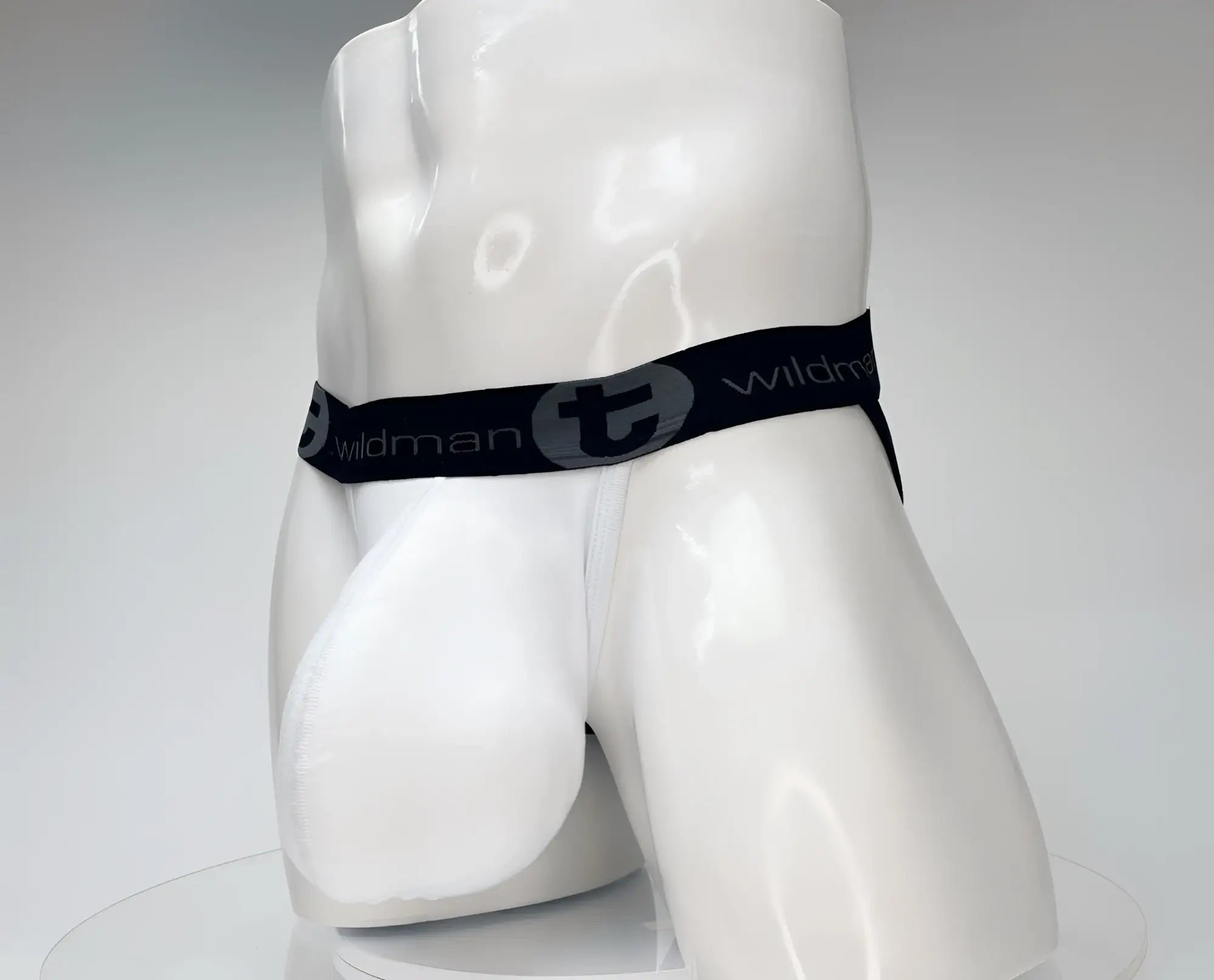 Black elastic waistband with wildman branding and stylized t logo on white cotton monster cock jockstrap displayed on mannequin