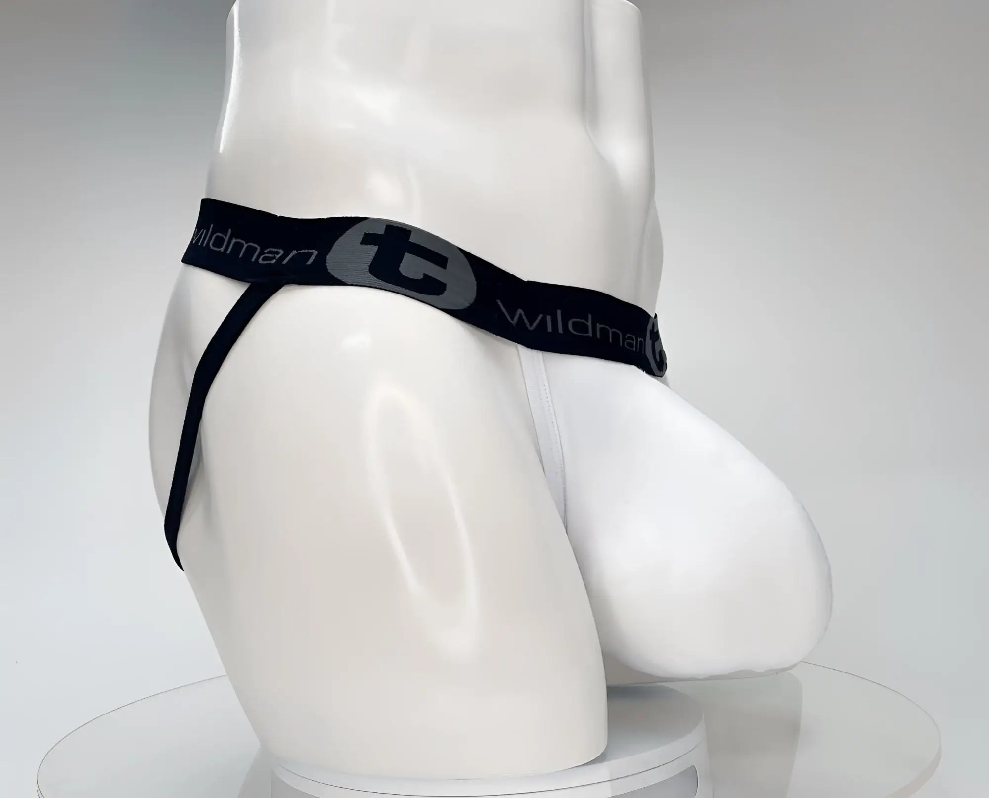 White men’s cotton thong with black elastic waistband featuring Wildman branding and gray logo for support wear
