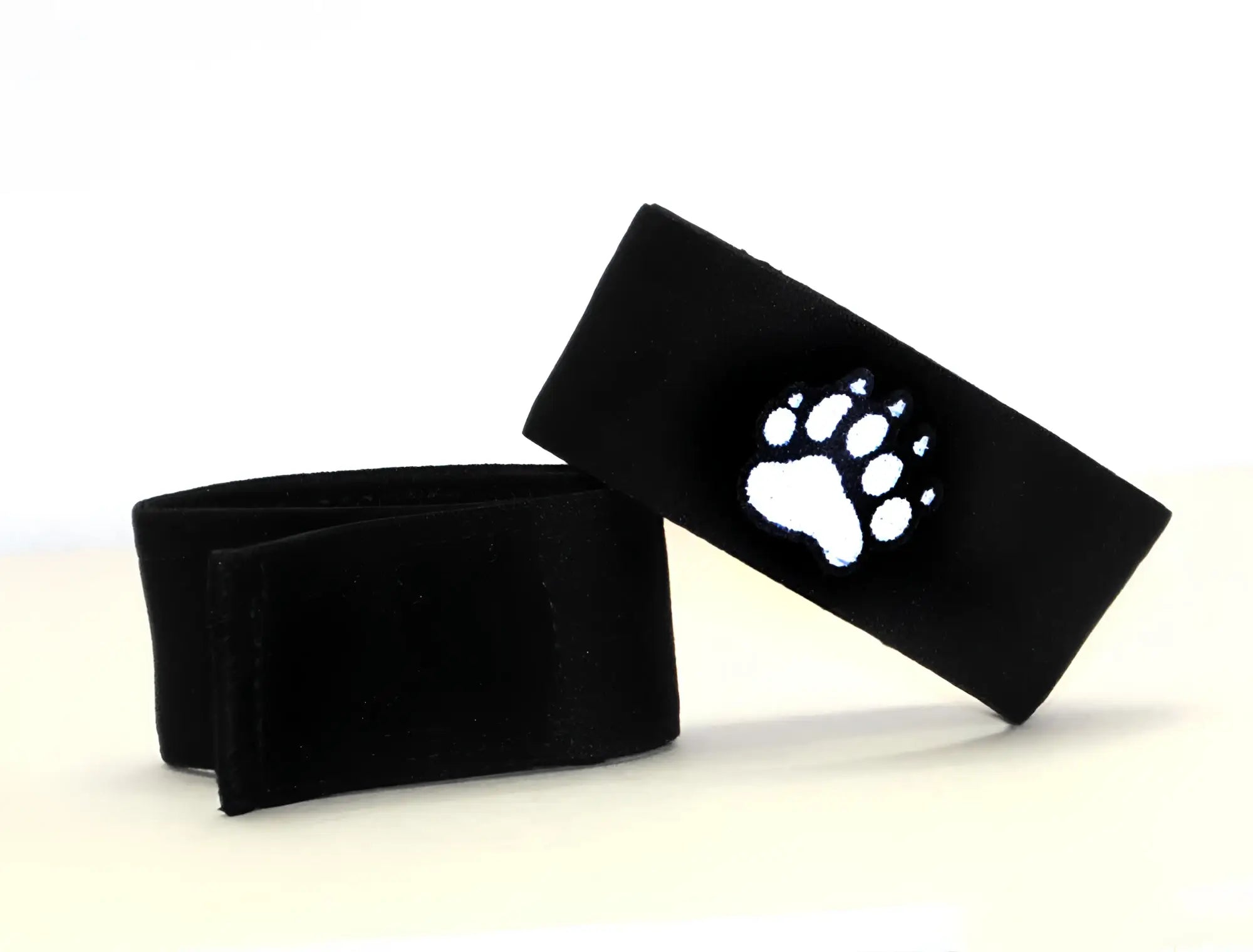 Black felt wristband with a white embroidered paw print design from wildmant fetish max cock ring bear collection