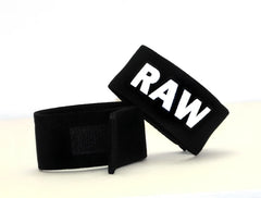 Black fabric wrist wraps with bold white raw lettering from wildmant fetish max cock ring raw product