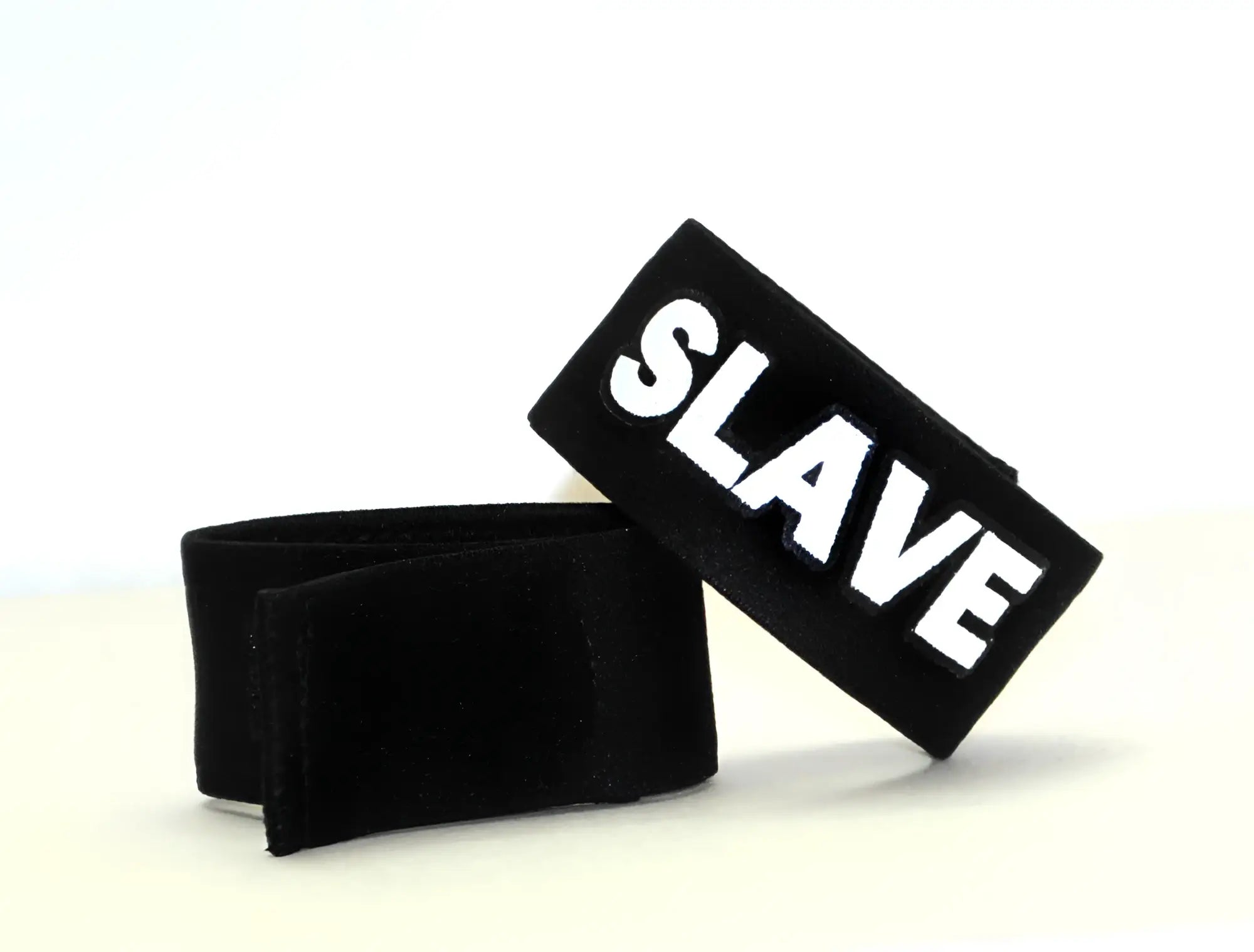 Black velour wristband with bold white embroidered slave lettering from wildmant fetish max cock-ring-slave collection