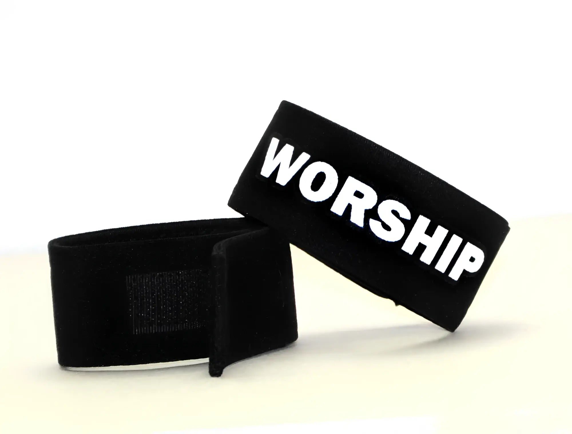 Black wristband with bold white worship lettering and velcro closure from wildmant fetish max cock-ring worship product