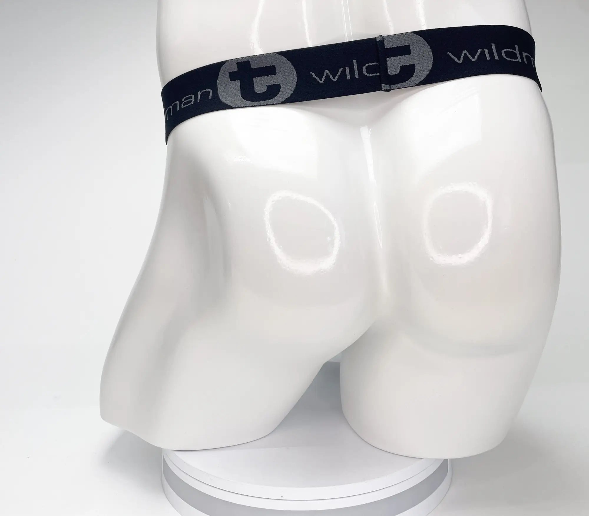 Black elastic waistband of wildmant mesh monster cock strapless pouch featuring gray wildman logo and stylized t emblem
