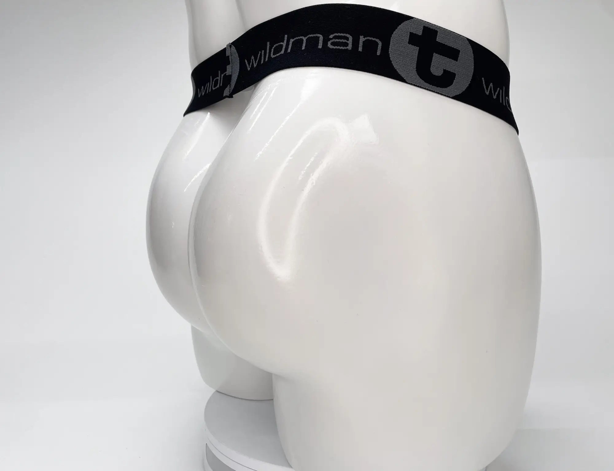 Black elastic waistband with wildman branding and circular logo on white mesh monster cock strapless pouch mannequin