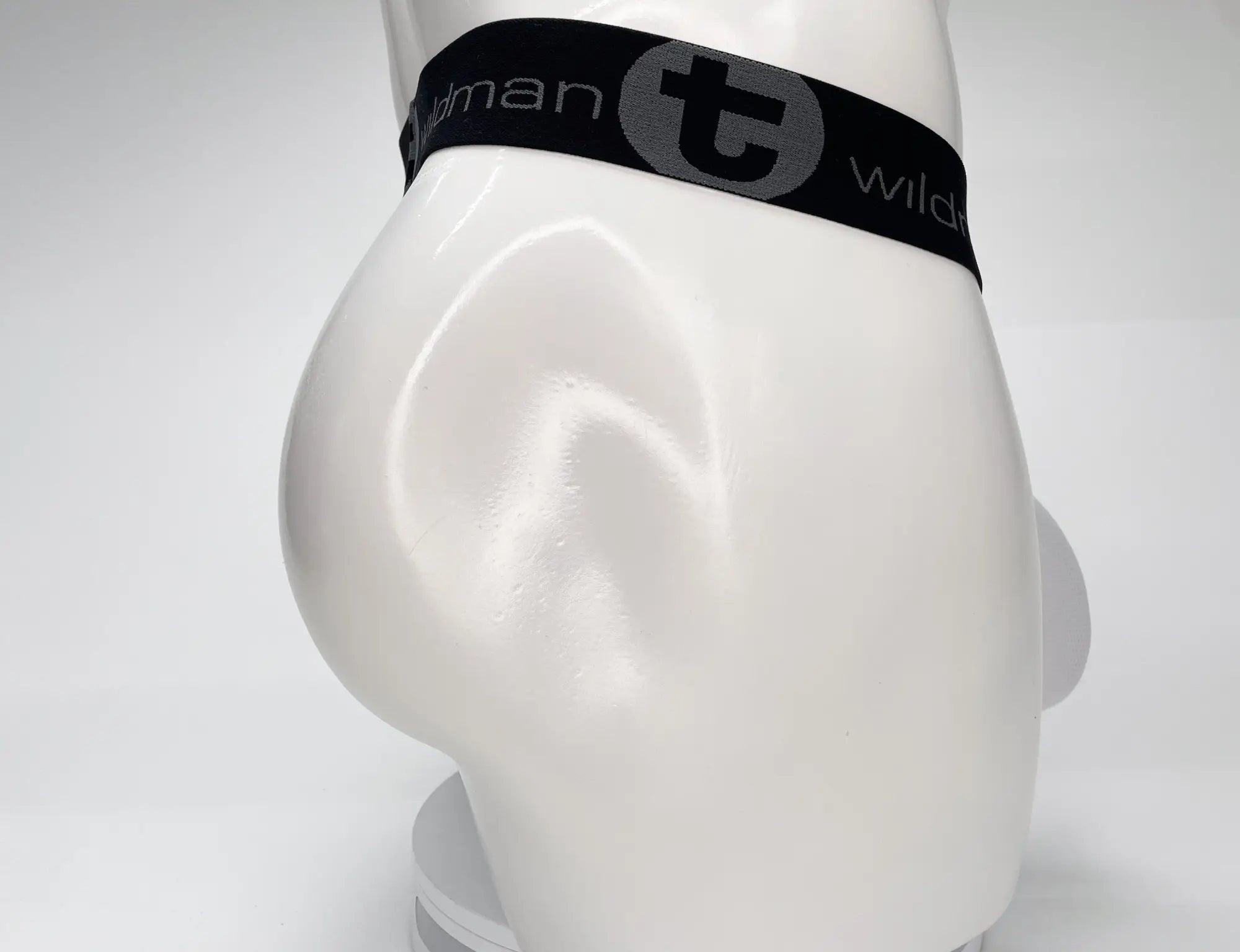 Black elastic waistband with gray t logo and wildman branding on white mesh monster cock strapless pouch