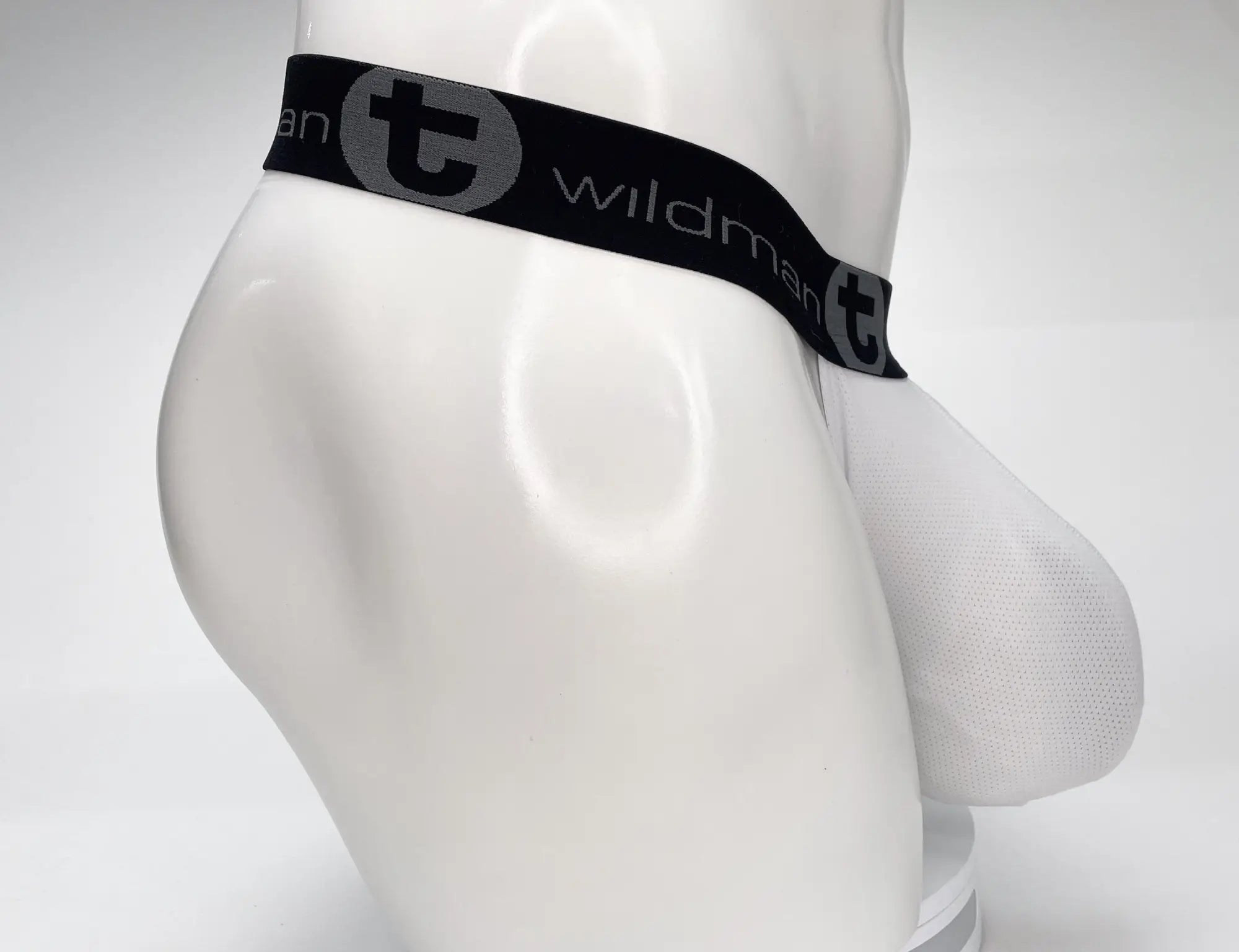 White mesh men’s briefs with black elastic waistband featuring wildman brand logo and gray circular emblem