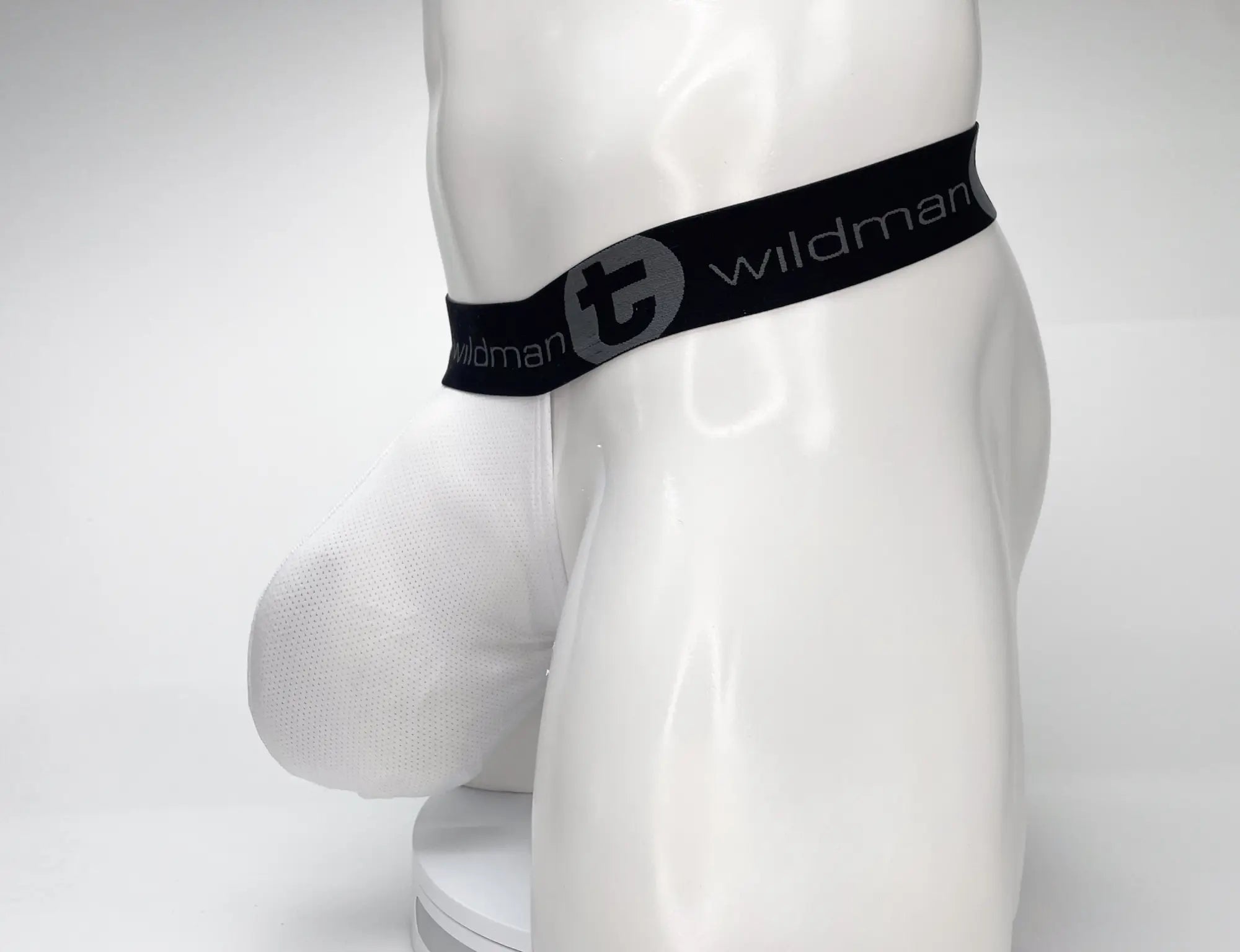 White wildman briefs with black elastic waistband and gray logo featuring mesh monster cock strapless pouch design