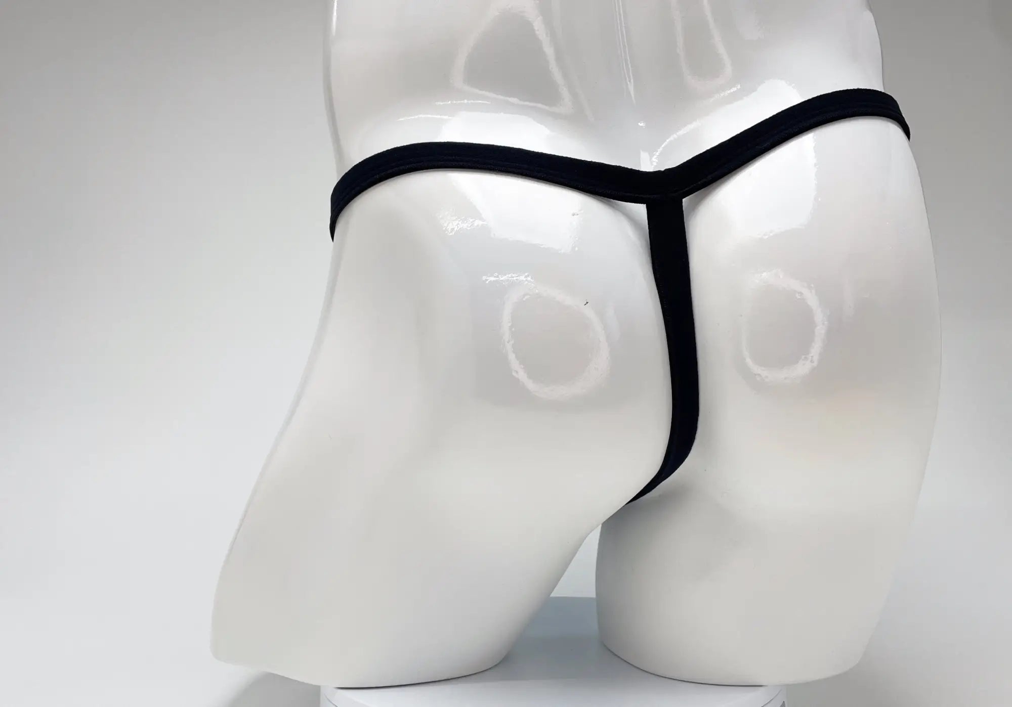 Black thong displayed on white mannequin highlighting wildmant modal micro thong big boy pouch in baby blue