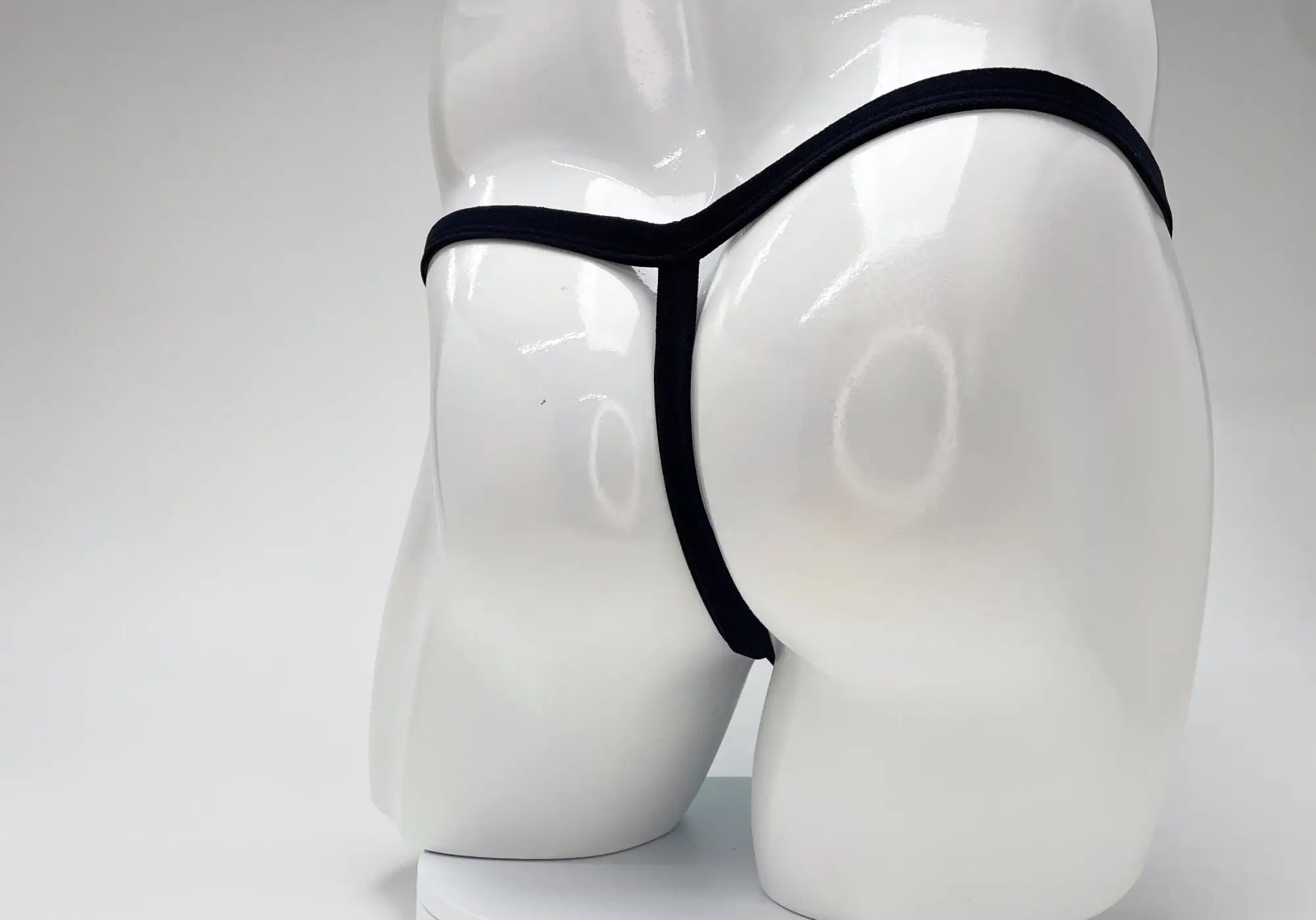 Black thong displayed on white mannequin featuring modal microfiber material and big boy pouch in baby blue color