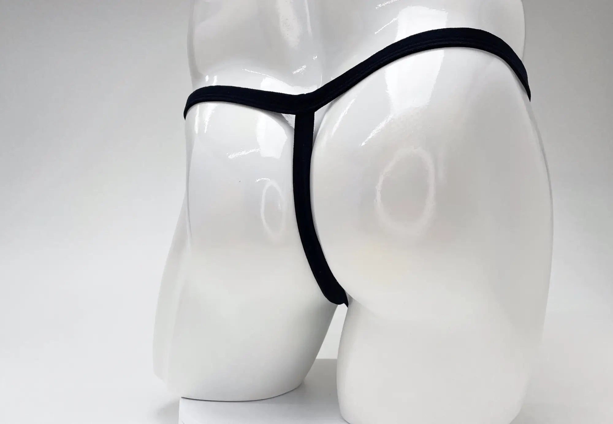 Wildmant modal micro thong black displayed on white mannequin highlighting big boy pouch design in gold trim