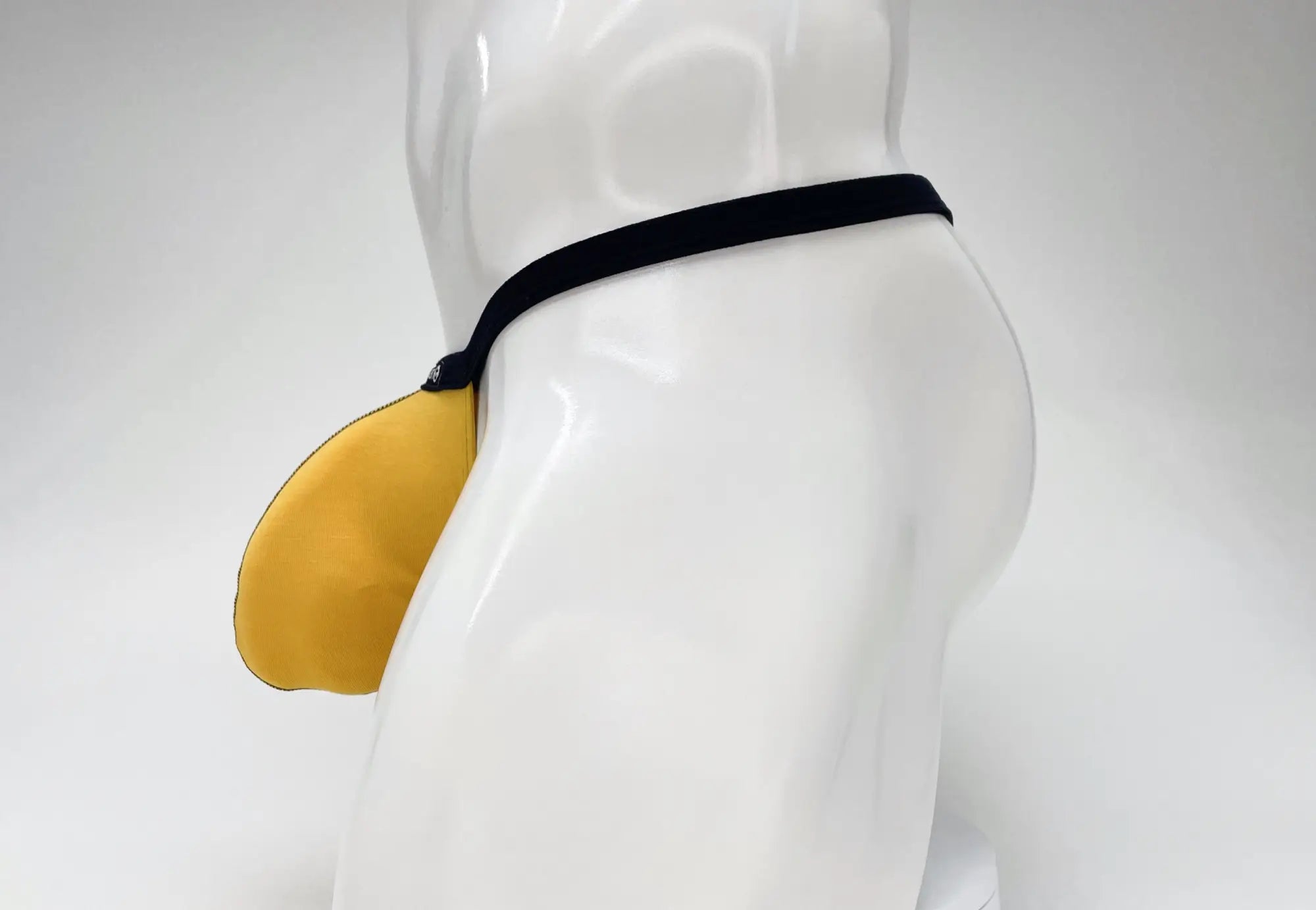 Yellow leather WildmanT Modal micro thong big boy pouch with black strap worn on mannequin front side