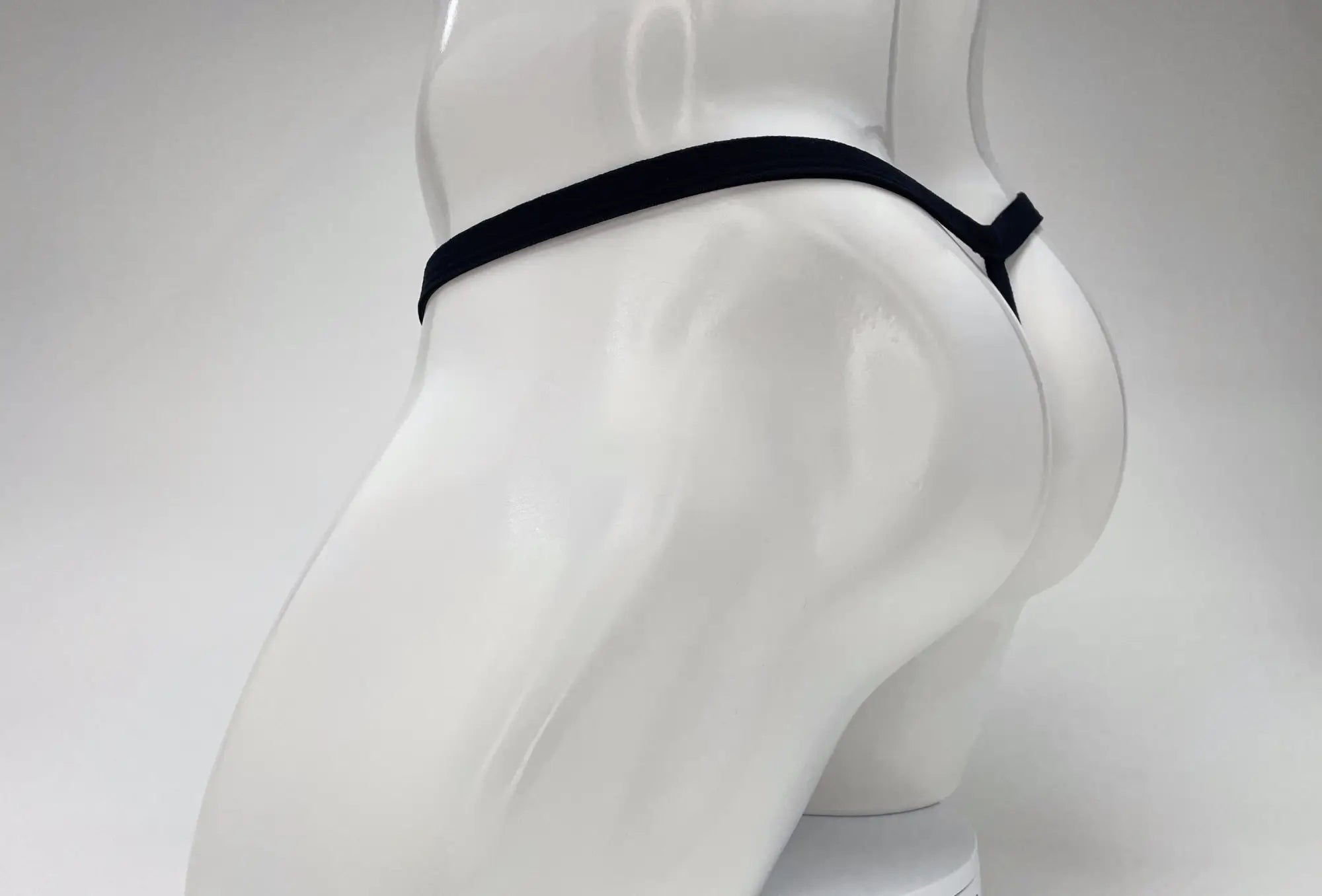 Black elastic waistband thong in modal material with pink big boy pouch displayed on white mannequin