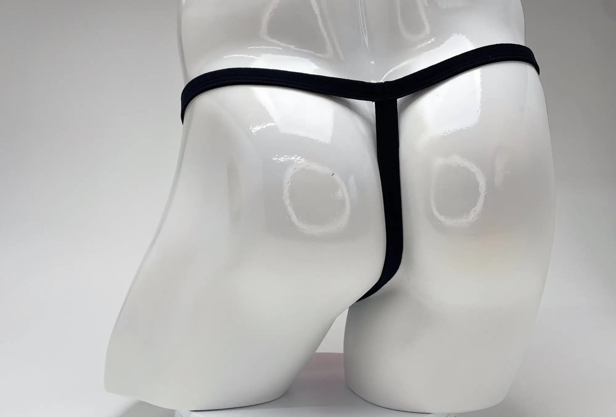 Black thong displayed on white mannequin wildmant modal micro thong big boy pouch pink front view