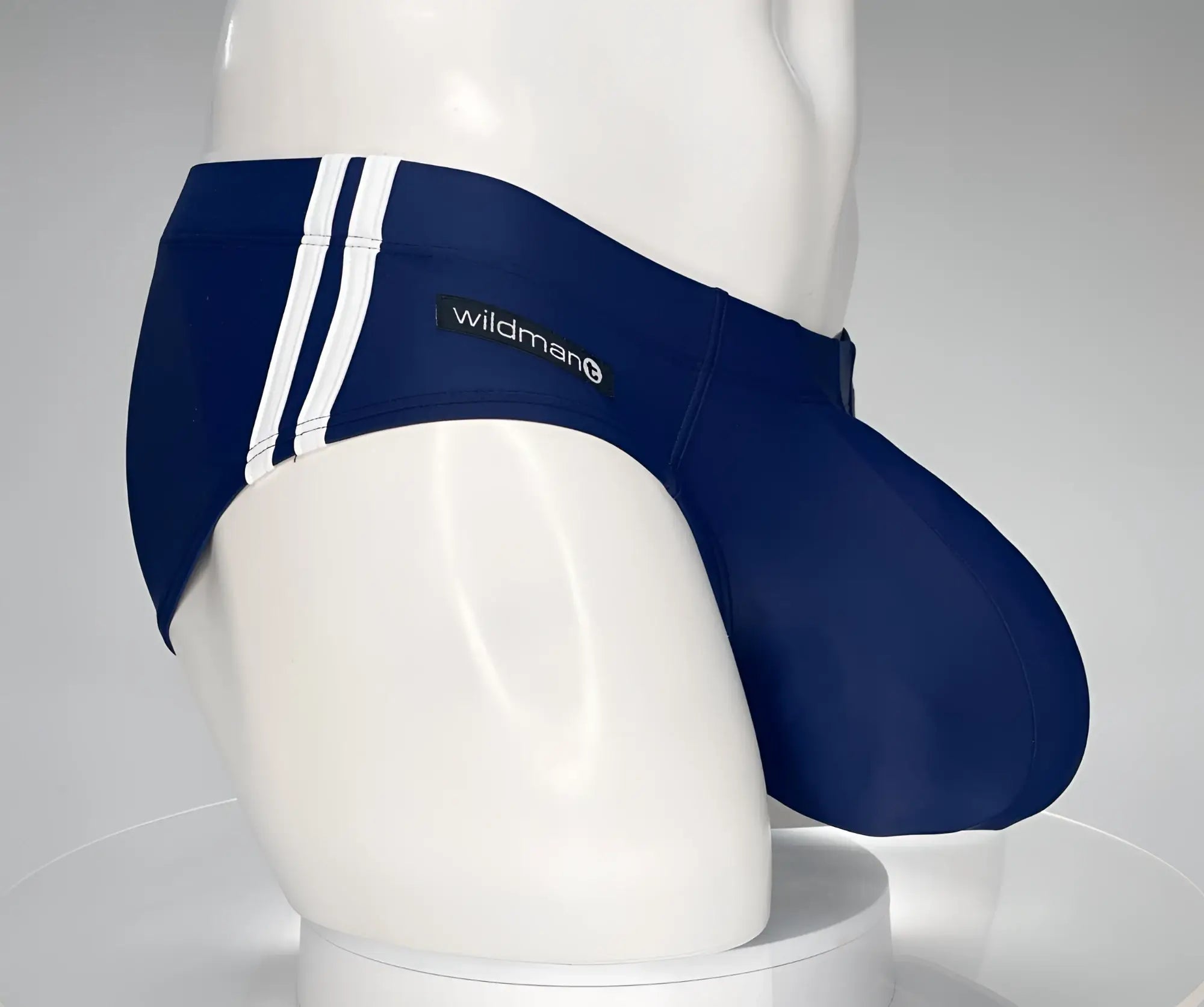 WildmanT monster cock navy swim brief featuring navy blue fabric with white vertical stripes and a wildman label