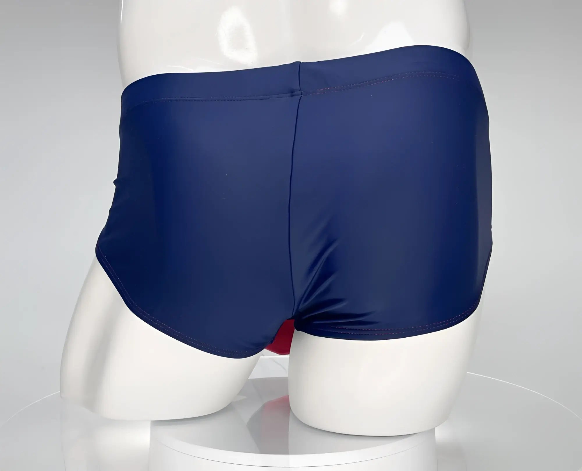 Navy blue swim trunks with a smooth, glossy fabric finish and a subtle seam down the center back