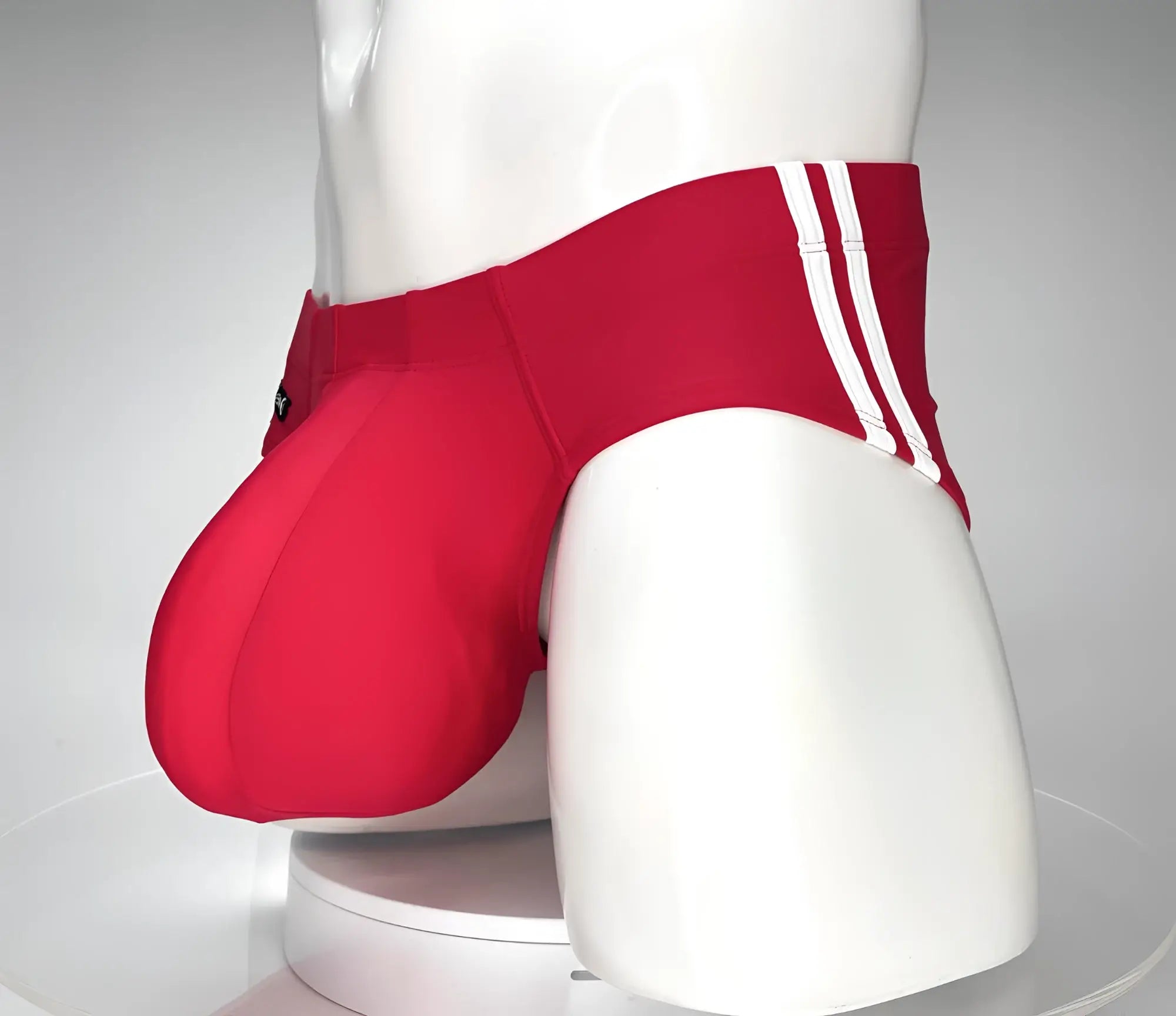 WildmanT Monster Cock swim brief red with three white stripes on the side displayed on a mannequin