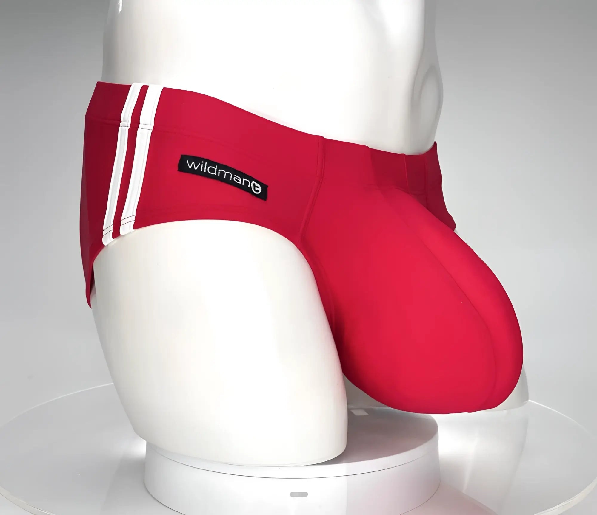 Red swim trunks with white side stripes and a black ’wildman’ brand label.