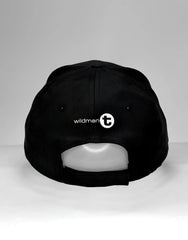 Black WildmanT vanity cap with white wildman t logo and circular emblem on the back side