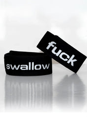 Black elastic wristband with white embroidered text reading fuck and swallow from wildmant verbal max cock-ring swallow