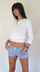 White long-sleeved cropped hoodie with front pocket and ribbed cuffs paired with baby blue yoga training shorts