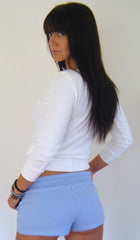A woman wearing baby blue yoga training shorts and a white long-sleeved crop top in a fitness setting